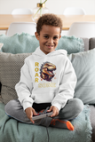 Young boy smiling on a couch wearing a white ROARSOME kids dinosaur hoodie with a T-Rex graphic.